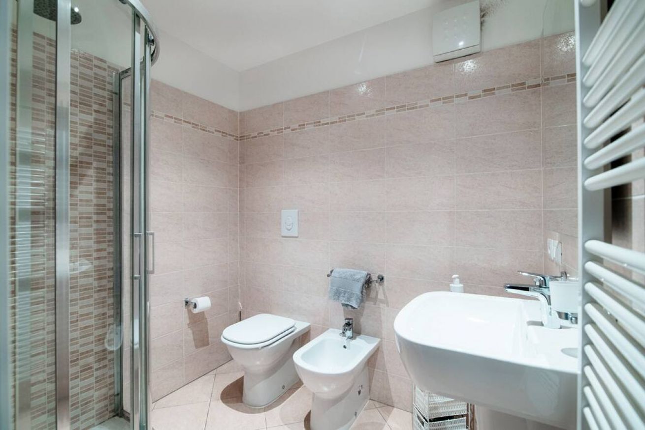 A bathroom with a glass shower enclosure, a toilet, a bidet, and a sink.