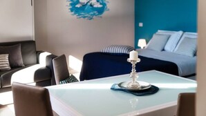 A hotel room with a bed, a table with a candle, a blue wall, and a sofa.