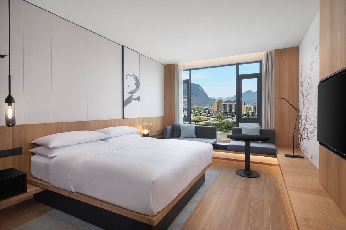 Une chambre d’hôtel moderne dotée d’un grand lit, d’un coin salon avec vue et d’une télévision.