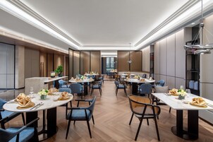 Un comedor moderno con mesas redondas, sillas azules y una isla central con una planta.