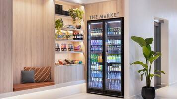 A modern retail space with wooden shelving, a seating area, and a refrigerated display case labeled "THE MARKET".