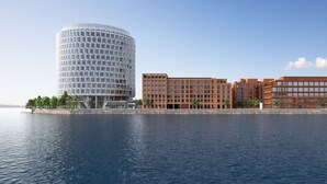 A waterfront hotel with a modern cylindrical building and adjacent multi-story structures. - Residence Inn By Marriott Copenhagen Nordhavn (Copenhagen)