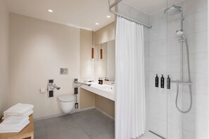 A modern bathroom with a shower, toilet, and sink.