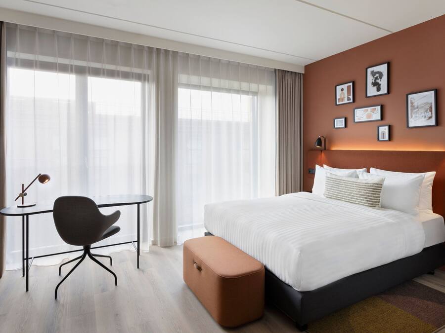 Una habitación de hotel moderna con una cama, un escritorio y una silla.