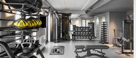 A gym with weightlifting equipment, dumbbells, and exercise machines.