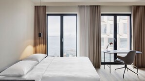 A hotel room with a bed, a desk, and a view of the sea. - Residence Inn By Marriott Copenhagen Nordhavn (Copenhagen)