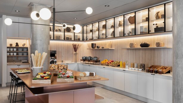 A modern kitchen with a central island, built-in cabinets, and a variety of food items and kitchenware displayed on shelves. - Residence Inn By Marriott Copenhagen Nordhavn (Copenhagen)