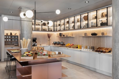 A modern kitchen with a central island, built-in cabinets, and a variety of food items and kitchenware displayed on shelves.