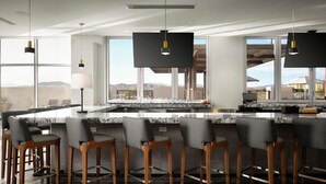 Una cocina moderna con una isla grande, taburetes de bar, lámparas colgantes y amplias ventanas con vistas a las montañas.