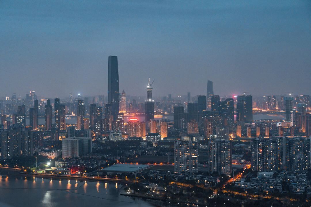 A cityscape at dusk with high-rise buildings, a river, and a prominent tower.