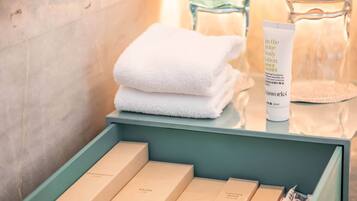 A bathroom vanity with neatly arranged toiletries including a tube of body lotion, a folded white towel, and several toiletry boxes.