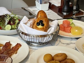 A dining table with various dishes including a salad, bread with olives, watermelon, and orange slices. - Wuhan Marriott Hotel Wuchang (Wuhan)