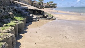 A beach with a concrete retaining wall, steps leading down to the shore, and a clear view of the ocean. - Village no Condominio Arauá, Fechado com Trilha Para Caminhada, Academia (Condomínio Arauá Vera Cruz)