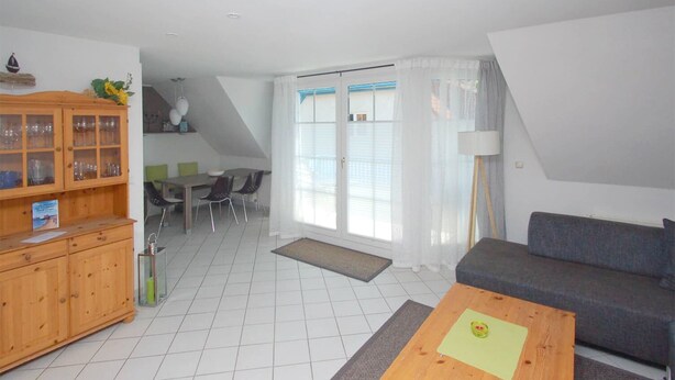 A modern living room with a sofa, a coffee table, and a dining area with chairs and a table. - Maisonette apartment for 4 persons, washing machine, WLAN, parking lot, quiet location (Prerow)