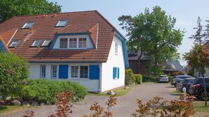 A two-story house with a sloped roof, dormer windows, and blue shutters. - Maisonette apartment for 4 persons, washing machine, WLAN, parking lot, quiet location (Prerow)