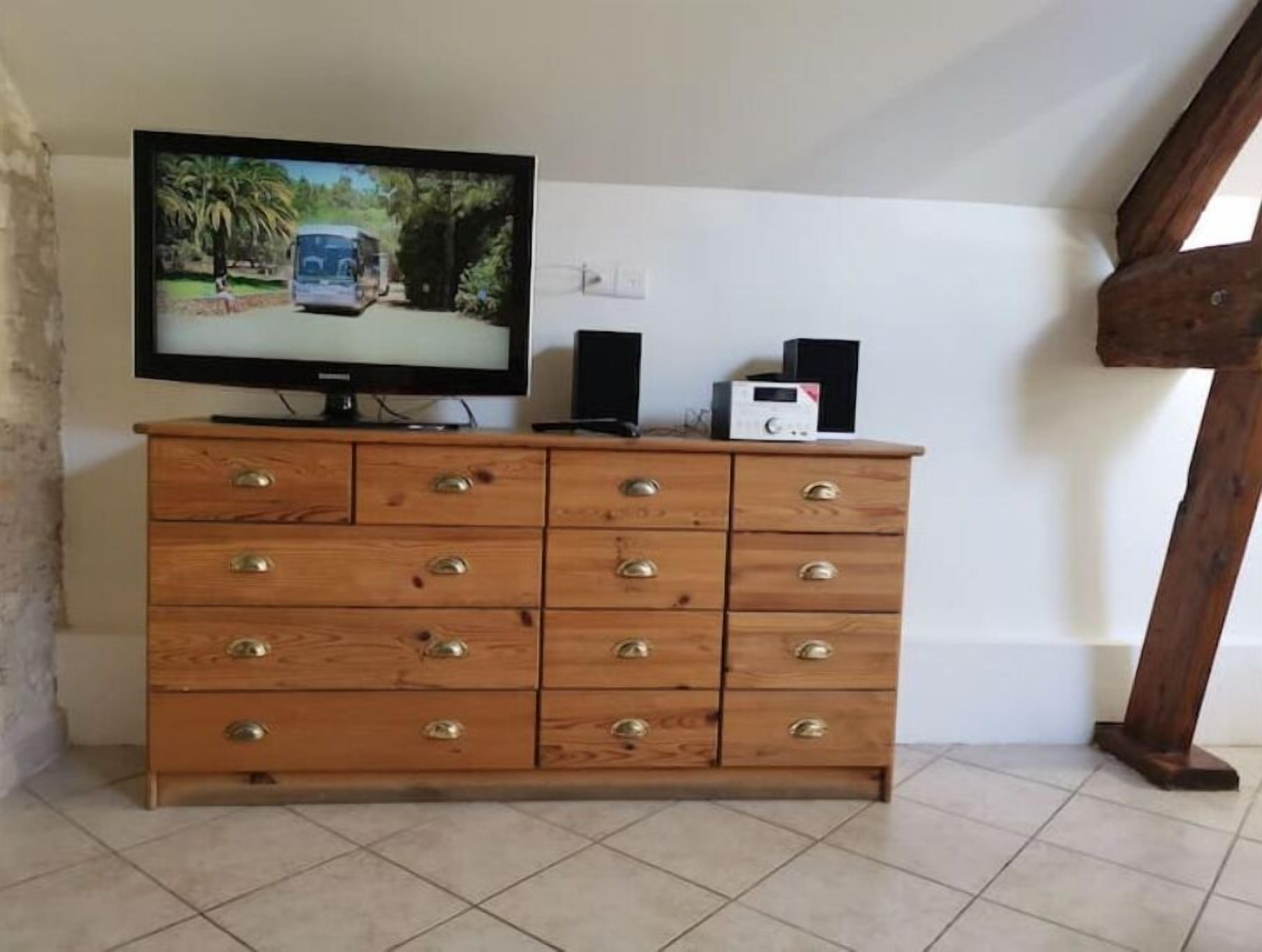 A wooden dresser with multiple drawers and a television on top.