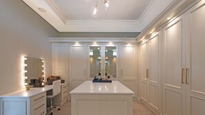 A well-lit walk-in closet with mirrored doors, a vanity with a mirror, and a central island. - Franschhoek Homestead Cottage (Franschhoek)