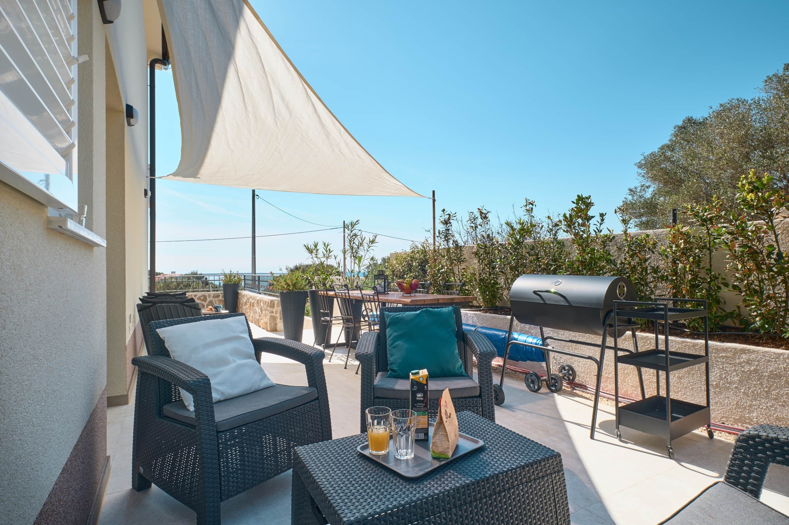 Un patio al aire libre con mobiliario de mimbre, una parrilla y una mesa con bebidas.