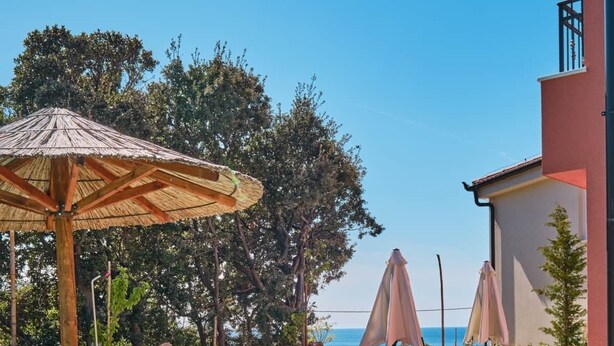 A pool area with lounge chairs and umbrellas, a wooden pergola, and a view of the sea. - MEACres Sun - secluded pool villa (Miholašćica)