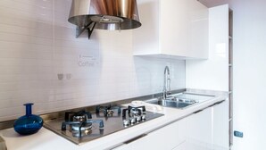 Uma cozinha moderna com azulejos brancos, eletrodomésticos de aço inoxidável e um vaso azul.