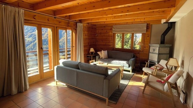 A cozy cabin interior with a sofa, a small table, and a fireplace. - Large, very bright chalet for 8 people with large terrace, garden and a beautiful open view.Interior (St-Luc)