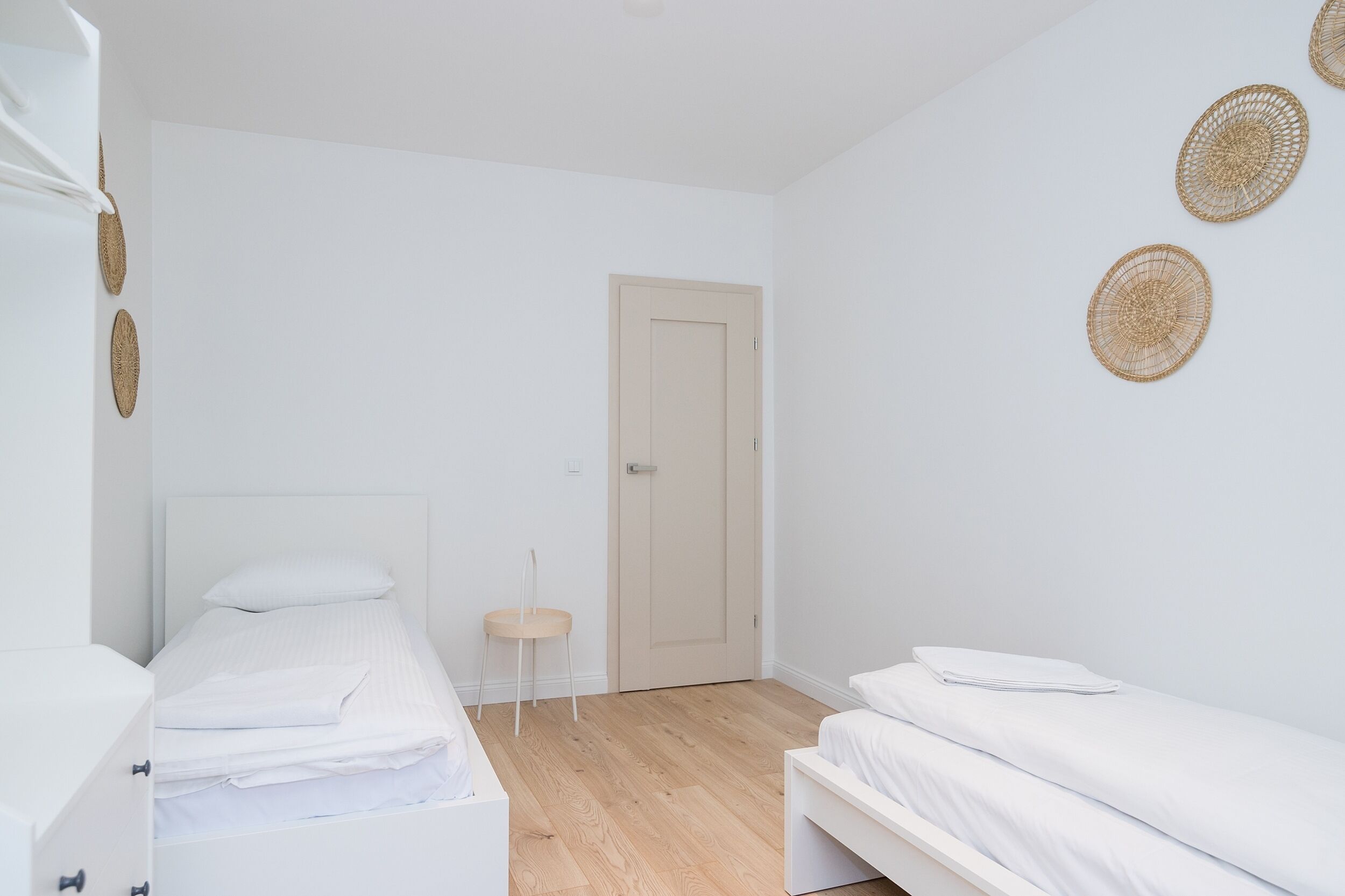 Une chambre à coucher minimaliste avec deux lits, un plancher en bois et une porte.
