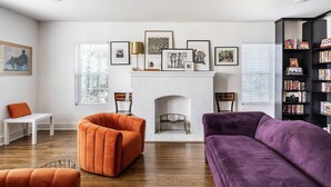 A living room with a fireplace, two armchairs, a bookshelf, and framed pictures on the wall. - Welcome to Unit B (Houston)
