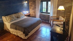 Un dormitorio con cama, mesita de noche, lámpara, silla y ventana con cortinas.