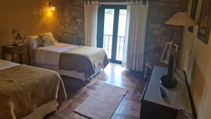 Una habitación acogedora con dos camas, una pared de piedra, techo de madera y vistas a través de un ventanal.
