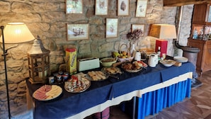 Una mesa de buffet con diversos alimentos y una pared de piedra con cuadros enmarcados.