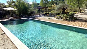 A rectangular swimming pool with clear water, surrounded by a wooden deck and lounge chairs. - Luxury villa in Gordes With Exceptional Views, Not Overlooked, Sleeps 16 (MURS)