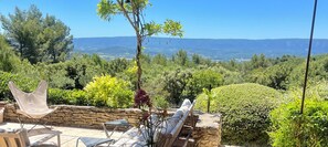 A terrace with stone walls, a hammock, and a view of a mountainous landscape. - Luxury villa in Gordes With Exceptional Views, Not Overlooked, Sleeps 16 (MURS)