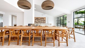 A spacious dining area with a long wooden table and chairs, large woven pendant lights, and a view of greenery through large windows. - Luxury villa in Gordes With Exceptional Views, Not Overlooked, Sleeps 16 (MURS)