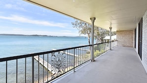 A covered balcony with a view of a calm body of water and distant land. - Silverwater Serenity Shores Absolute Waterfront (Silverwater)
