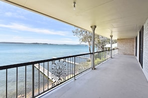 Ein überdachter Balkon mit Blick auf ruhiges Wasser und die Ferne.