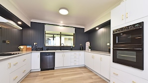 A modern kitchen with white cabinets, a black oven, and a dishwasher. - Silverwater Serenity Shores Absolute Waterfront (Silverwater)