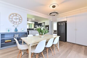 A modern kitchen with a dining table, chairs, and a clock on the wall. - Silverwater Serenity Shores Absolute Waterfront (Silverwater)