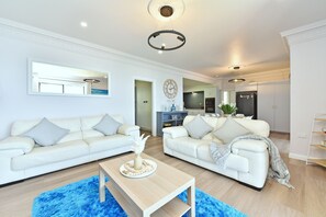 A modern living room with two white sofas, a coffee table, and a blue rug.