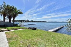 A waterfront property with a grassy lawn, a dock, and a boat. - Silverwater Serenity Shores Absolute Waterfront (Silverwater)