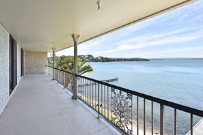 A balcony with a view of a calm body of water, a clear sky, and distant land. - Silverwater Serenity Shores Absolute Waterfront (Silverwater)