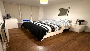 A bedroom with a bed, bedside table, nightstand, desk, and a ceiling light.