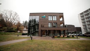 Un bâtiment moderne doté d’une façade en verre, d’un logo et d’un escalier menant à l’entrée.