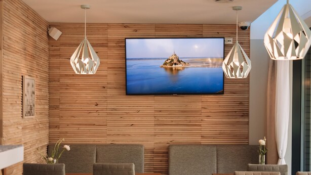 Un intérieur moderne avec un mur en bois, un téléviseur à écran plat et un coin repas comprenant des chaises et une table.