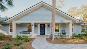 A light blue building with a porch, numbered 12, and a sign indicating it is a beachside getaway. - 12 Heron Street- The Happy Heron (Hilton Head Island)