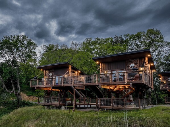 A rustic cabin with a balcony and a staircase leading to an upper level. - Two Treehouses + Bridge | Double 20-Foot Slides | Smoky Mountain Views (Sevierville)