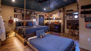 A room with two beds, a desk, and a chair. There are posters on the walls and a flag. - Two Treehouses + Bridge | Double 20-Foot Slides | Smoky Mountain Views (Sevierville)