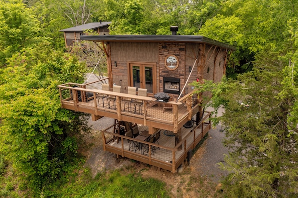 A wooden cabin with a deck, outdoor seating, and a fireplace.
