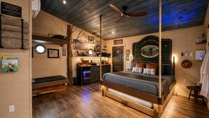 A room with a wooden floor, a bed with a canopy, a ceiling fan, and a wall-mounted TV. - Luxury Treehouse | Golf + Smoky Mountain Views | Slide | Sleeps 6 (Sevierville)
