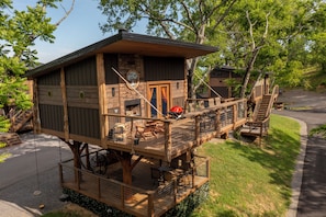 A wooden cabin with a deck, a fireplace, and a staircase leading to an upper level.