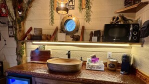 A kitchen with a wooden countertop, a round sink, a microwave, and a coffee bar. - Smoky Mountain Luxury Treehouse | 20-Foot Slide | Secret Beds | Sleeps 6 (Sevierville)